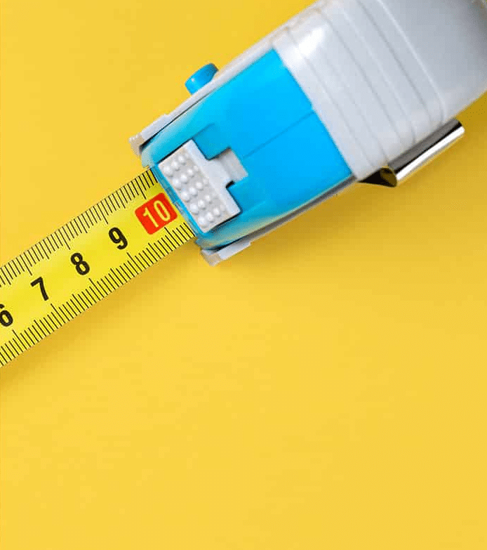 A top-down, close-up shot of a blue and grey retractable tape measure extending across a vibrant yellow background, with the "10" mark highlighted in red.