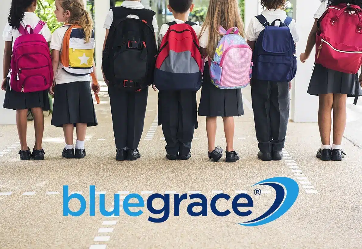 A row of schoolchildren from behind wearing colorful backpacks with the BlueGrace logo below.