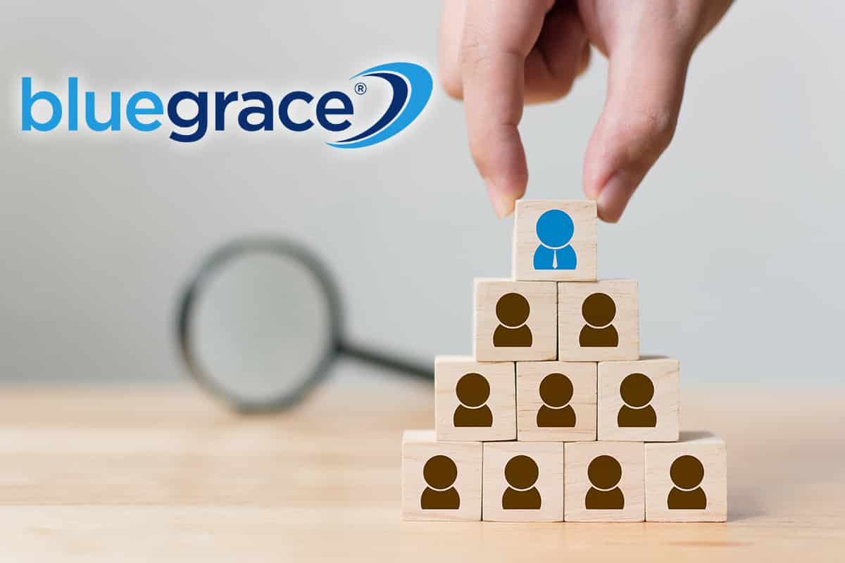 Hand placing a block with a blue person icon on top of a pyramid of blocks with brown person icons.