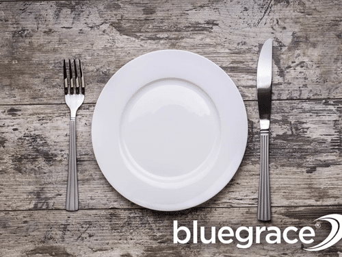 Top-down view of an empty plate and silverware on a rustic wooden table, symbolizing food scarcity and hunger pains caused by trucker shortages.