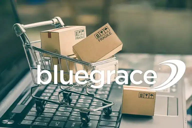 Miniature shopping cart with "Fragile" boxes on a laptop keyboard with the BlueGrace logo.
