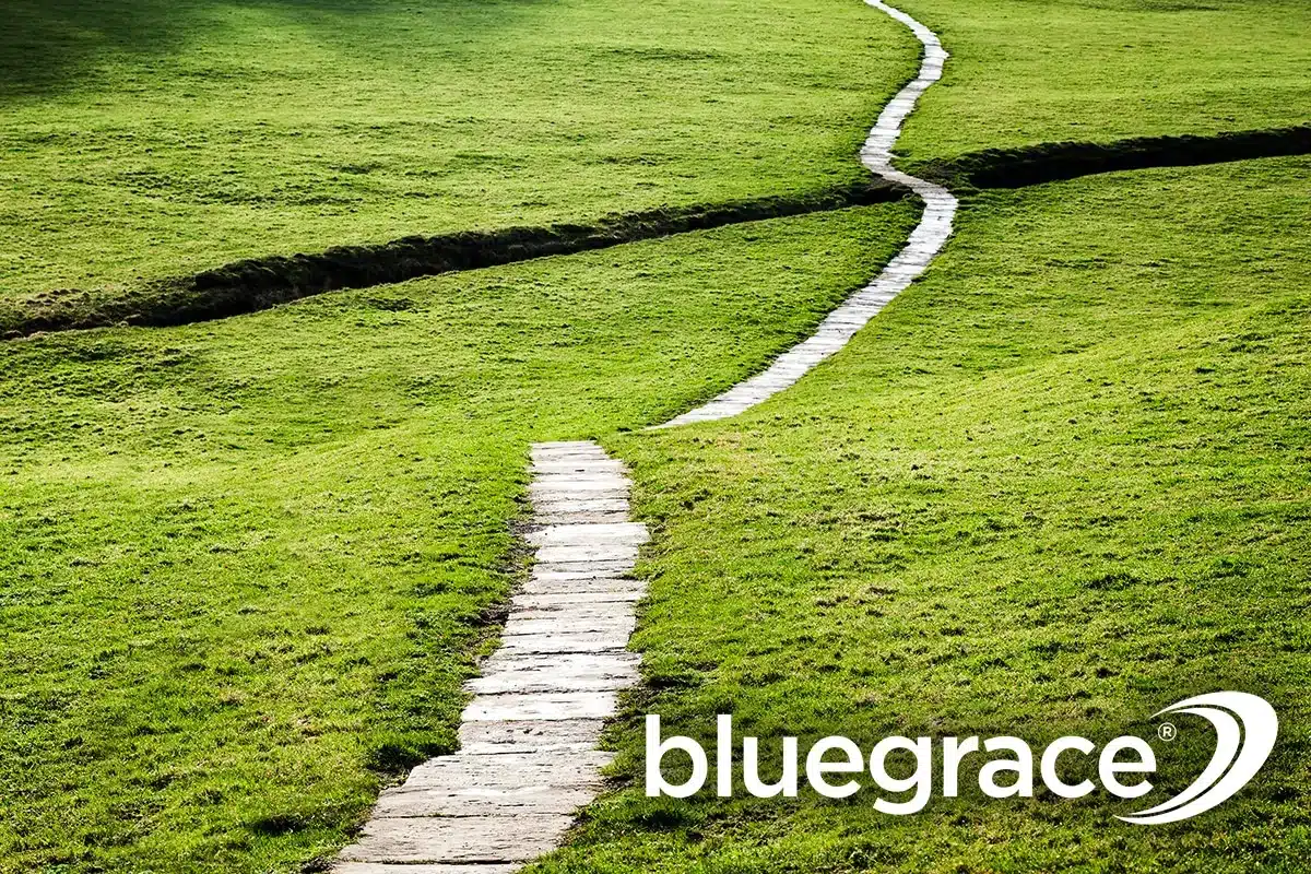 Stone walkway winding through a lush green grassy field under the BlueGrace logo.