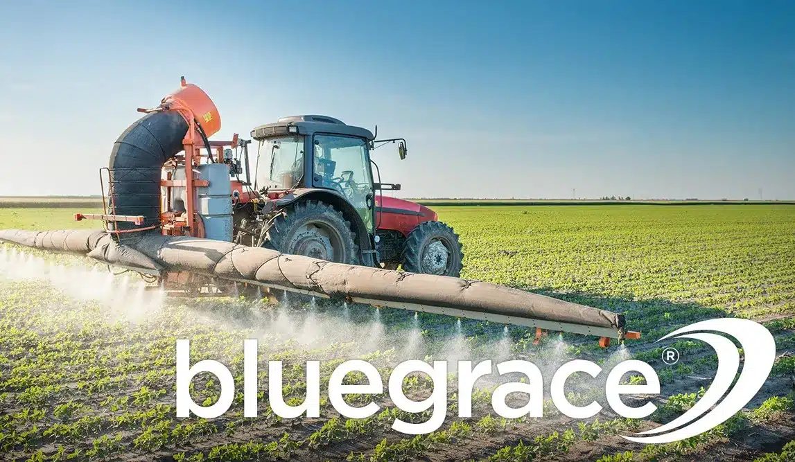Tractor spraying a large green crop field under a clear sky with the BlueGrace logo.