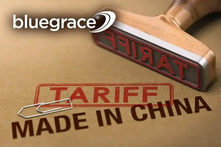 A wooden stamp with the word "TARIFF" in red ink is shown next to a "MADE IN CHINA" label on a cardboard surface, featuring the BlueGrace logo.