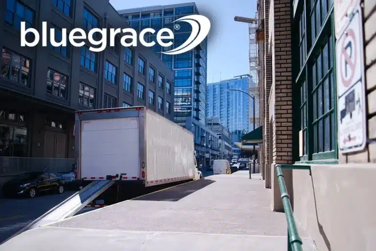 White delivery truck with loading ramp at an urban warehouse with BlueGrace logo.