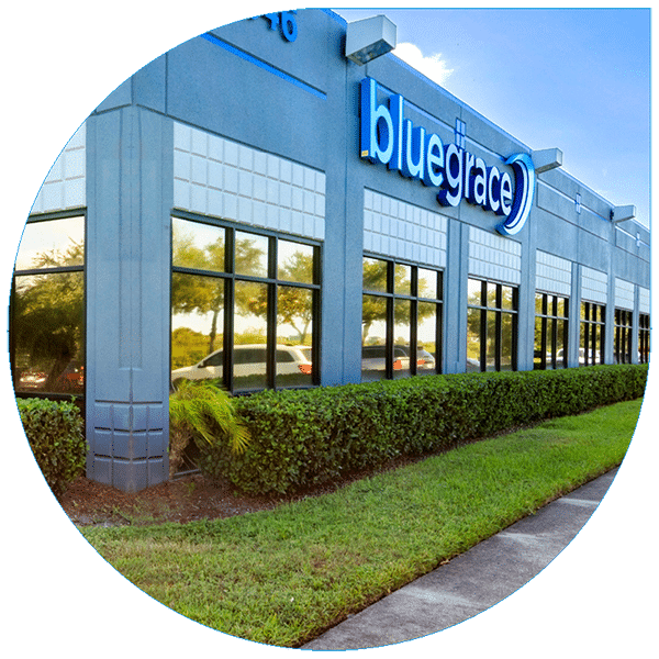 External view of a modern BlueGrace corporate office building featuring professional blue-and-white branding, reflective windows, and manicured landscaping.