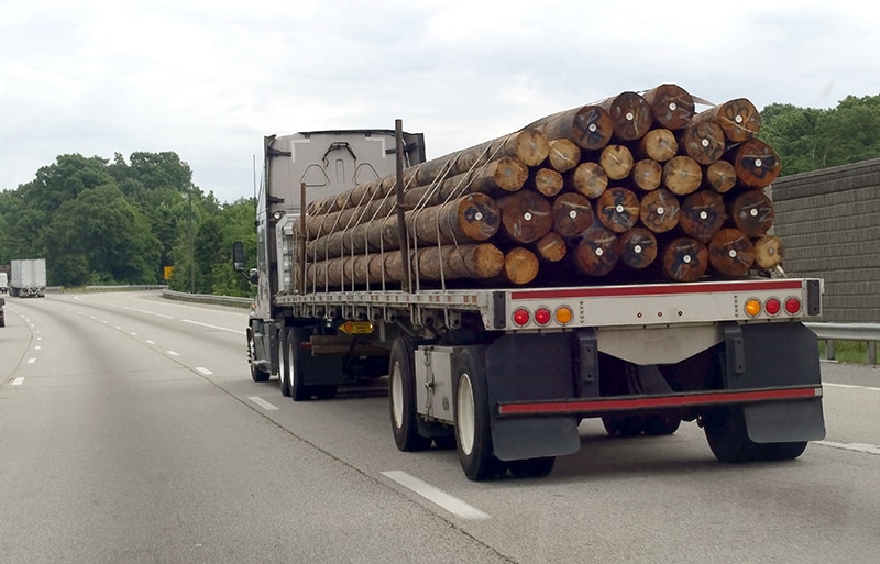 Rear view of flatbed semi truck hauling a cargo of telephone poles