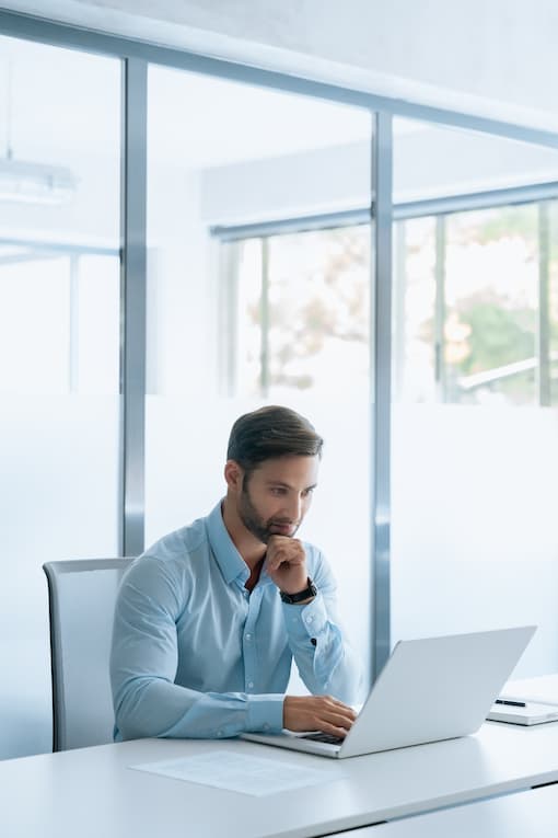 man sitting in bright meeting room working on laptop