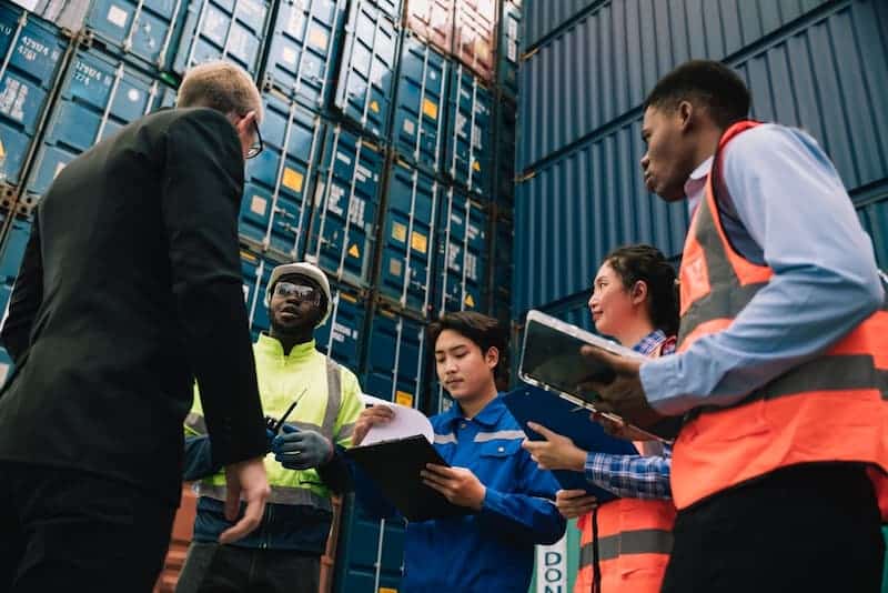 worker team meeting near shipping containers