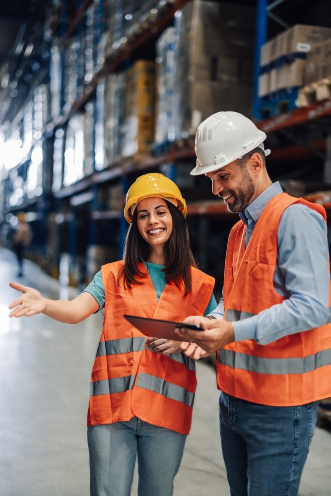 two warehouse workers looking at something on clipboard