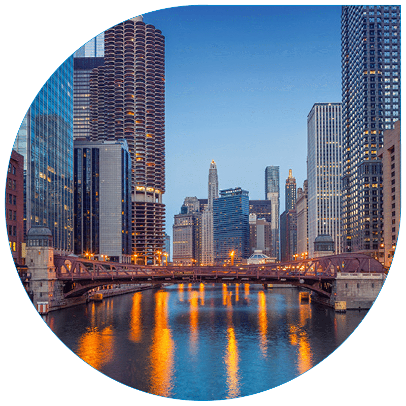 Twilight view of a large Chicago urban bridge crossing a river, flanked by modern skyscrapers and architectural buildings reflecting in the water.