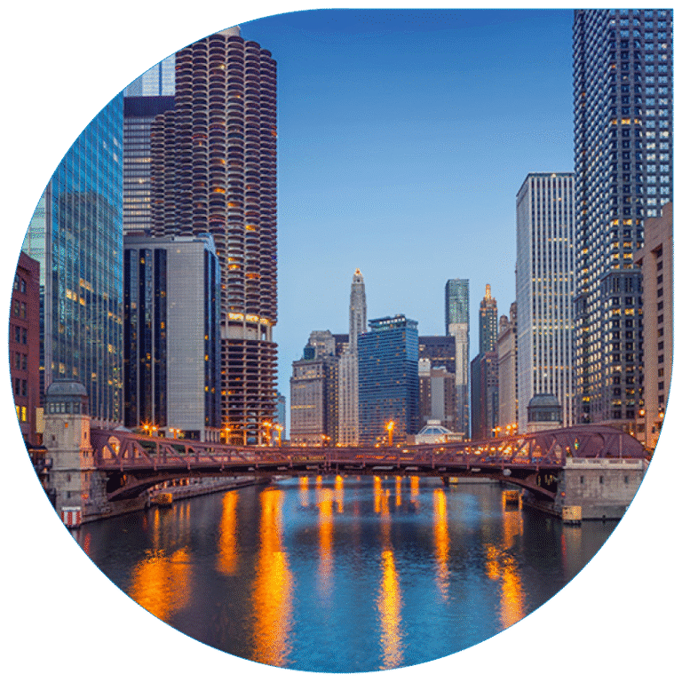 Twilight view of a large Chicago urban bridge crossing a river, flanked by modern skyscrapers and architectural buildings reflecting in the water.