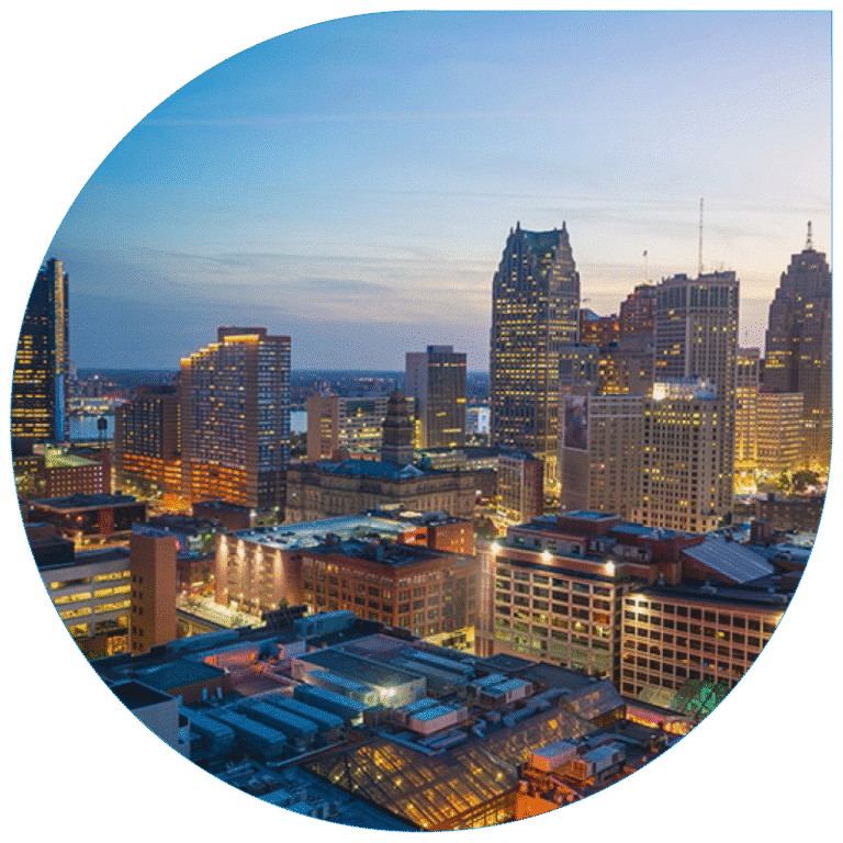 High-angle evening view of the Detroit metropolitan skyline featuring a mix of modern skyscrapers and historical industrial architecture.