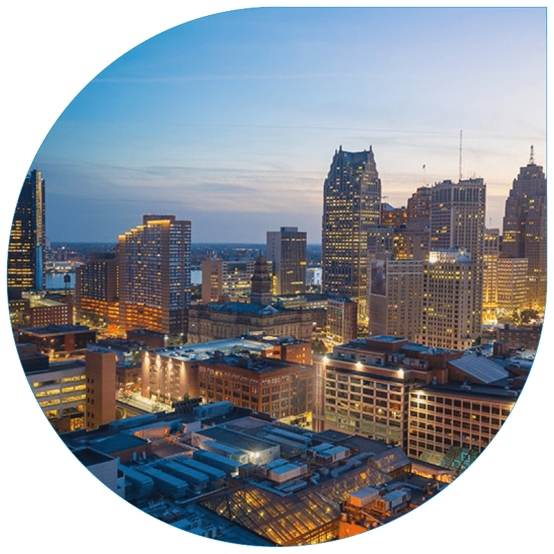 High-angle evening view of the Detroit metropolitan skyline featuring a mix of modern skyscrapers and historical industrial architecture.