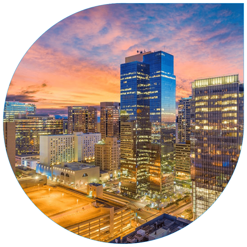 High-angle sunset view of the Phoenix urban skyline featuring modern glass skyscrapers, city streets, and architectural lighting.