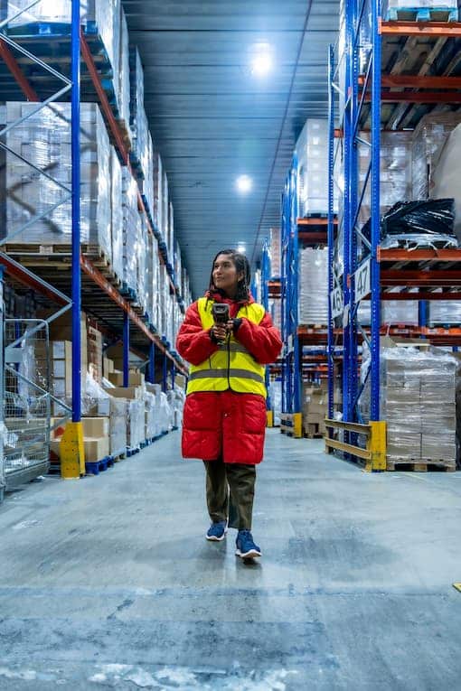 warehouse worker walking down refrigerated warehouse aisle