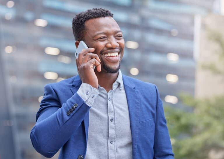 businessman smiling while talking on his cellphone outside building