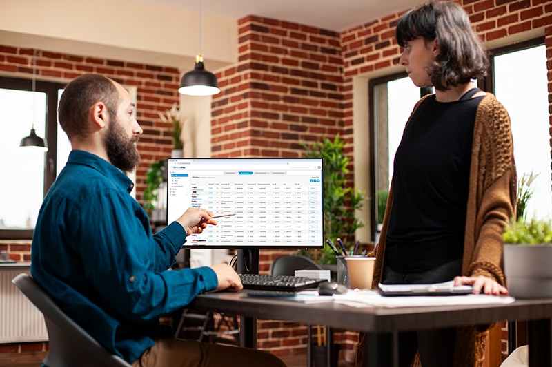Logistics professionals discussing shipment data on the BlueShip platform in a modern brick-walled office