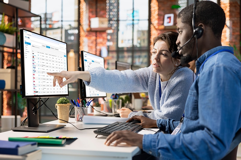 Call center agents collaborating to solve problem for customer, tracking lost shipments in office.