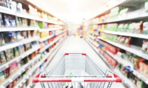 Retail blurry view of shopping cart in the middle of a grocery store aisle
