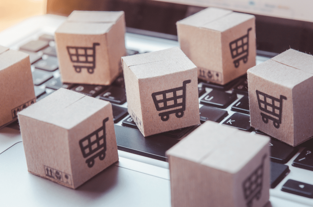 Wooden blocks with shopping cart icons placed on a laptop representing logistics management concepts